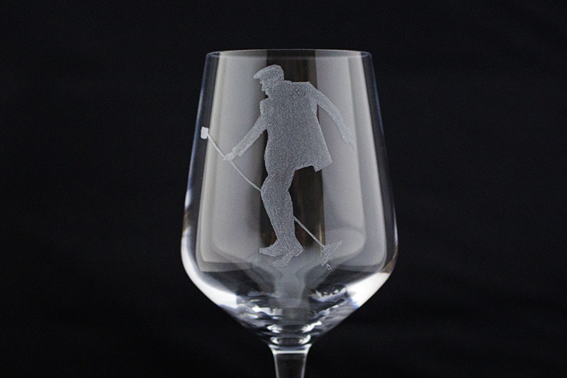 Close up of a wine glass hand engraved with Elvis doing his trade mark pose with a mic stand