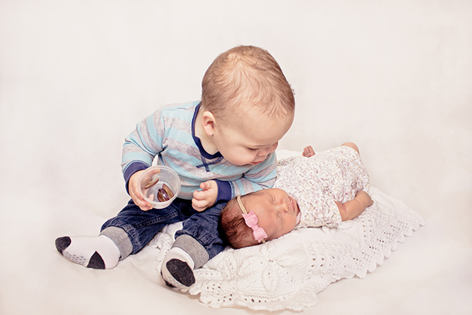 Big brother giving his baby sister a kiss on the head.
